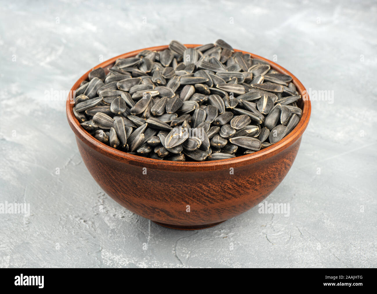 Large ceramic bowl with sunflower seeds on concrete background Stock Photo