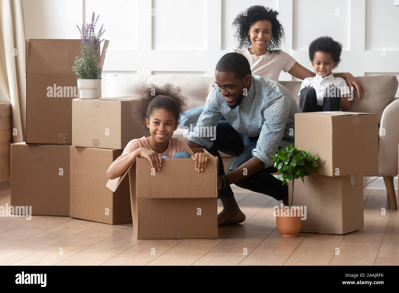African father riding daughter sitting inside of big carton box Stock Photo