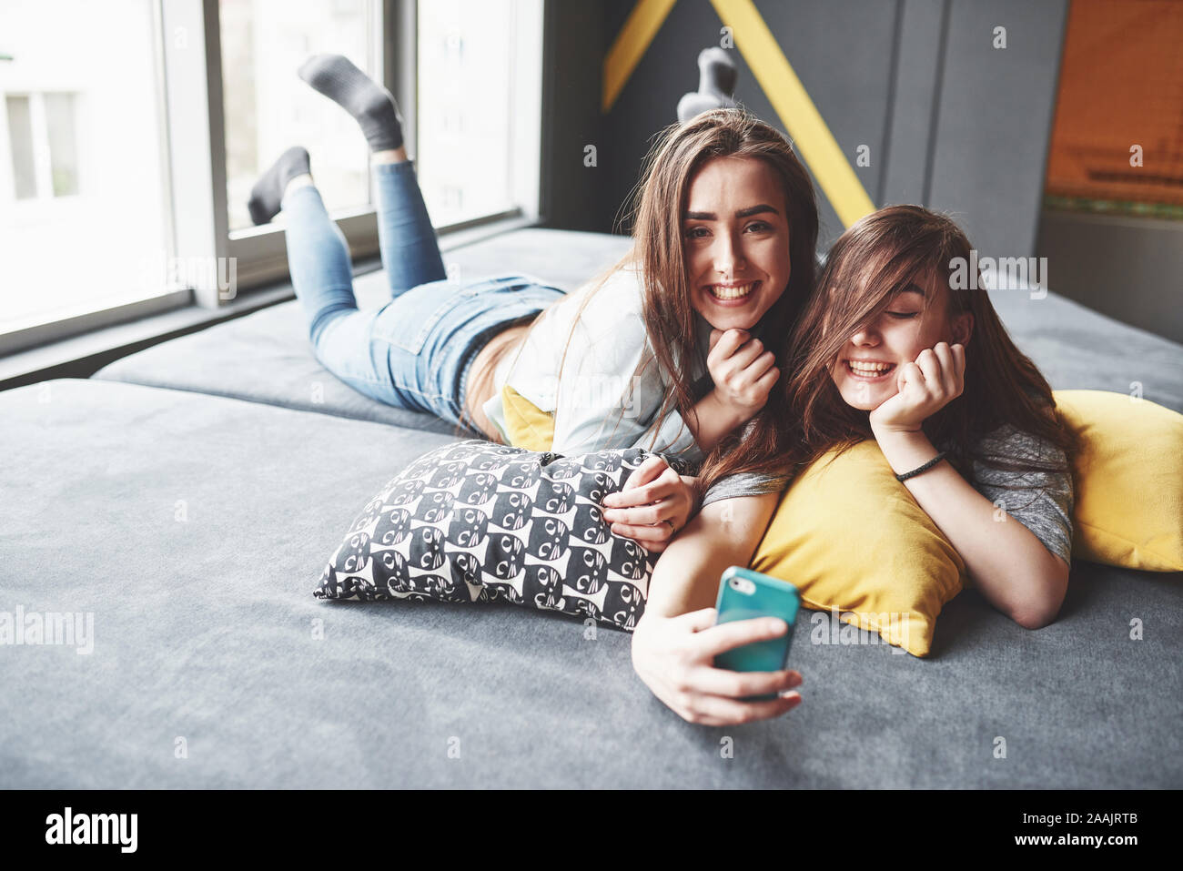 Two cute smiling twins sisters holding smartphone and making selfie 
