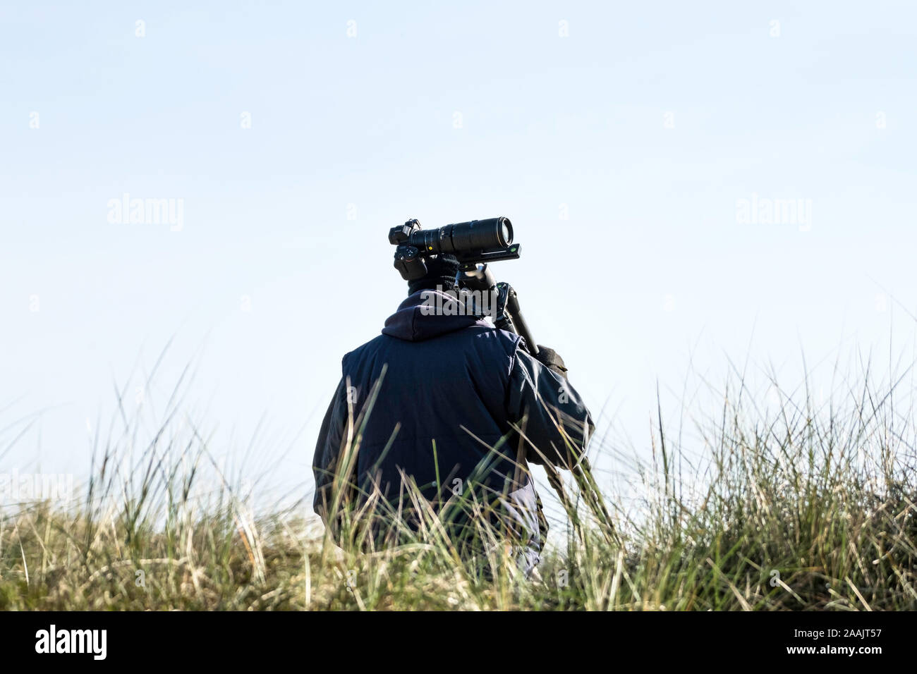 Photographer carry the tripod and camera at the beach during winter ...