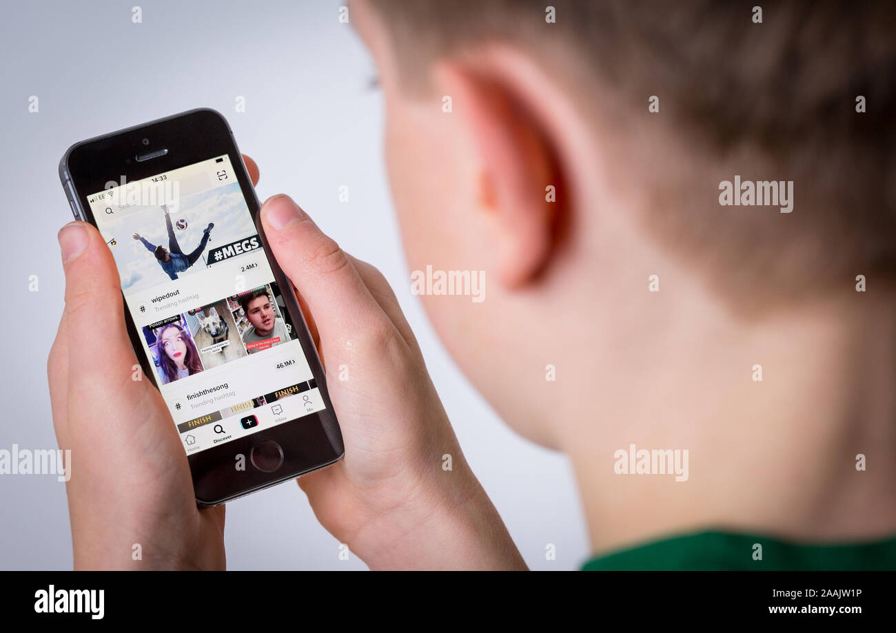 A Teenage boy using the TikTok app on a mobile phone Stock Photo