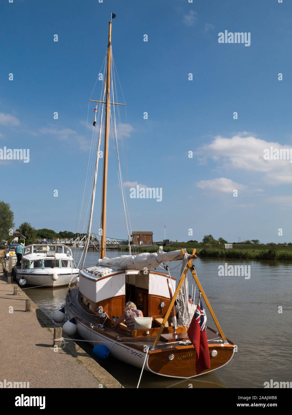 Sailing Boat and River Cruiser moored on the River Yare, part of The Norfolk Broads National Park, at the Village of Reedham, Norfolk, England, UK Stock Photo