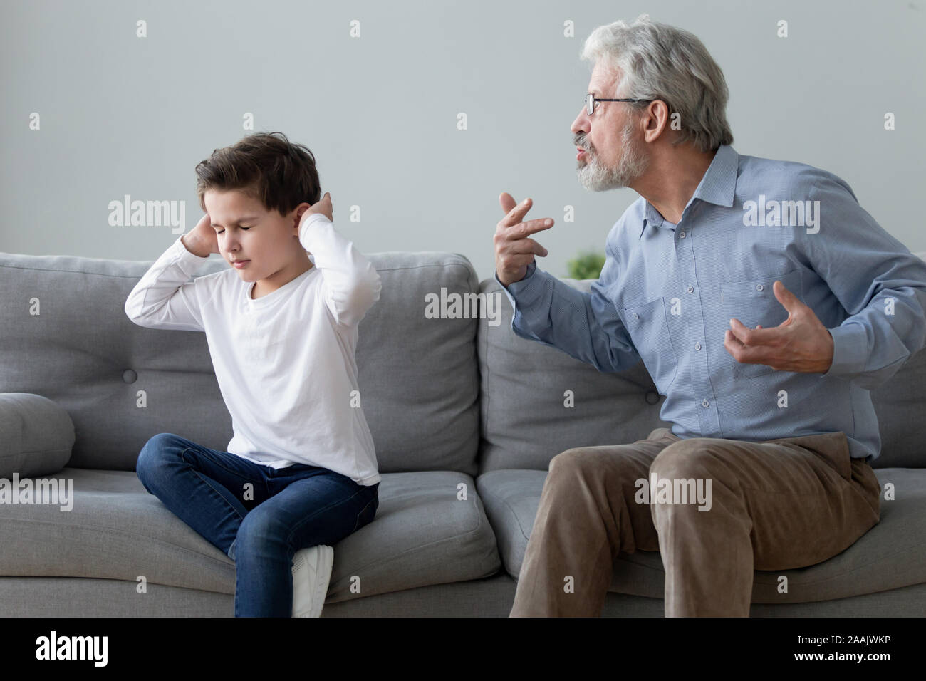 Stubborn naughty grandson ignoring strict annoyed grandfather Stock Photo