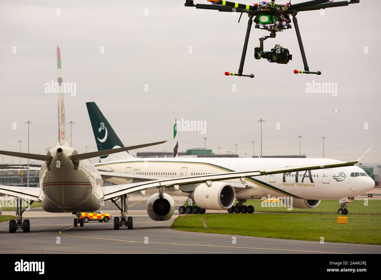 Planes taxiing towards arrivals at Manchester Airport, UK  with a drone flying over. Stock Photo