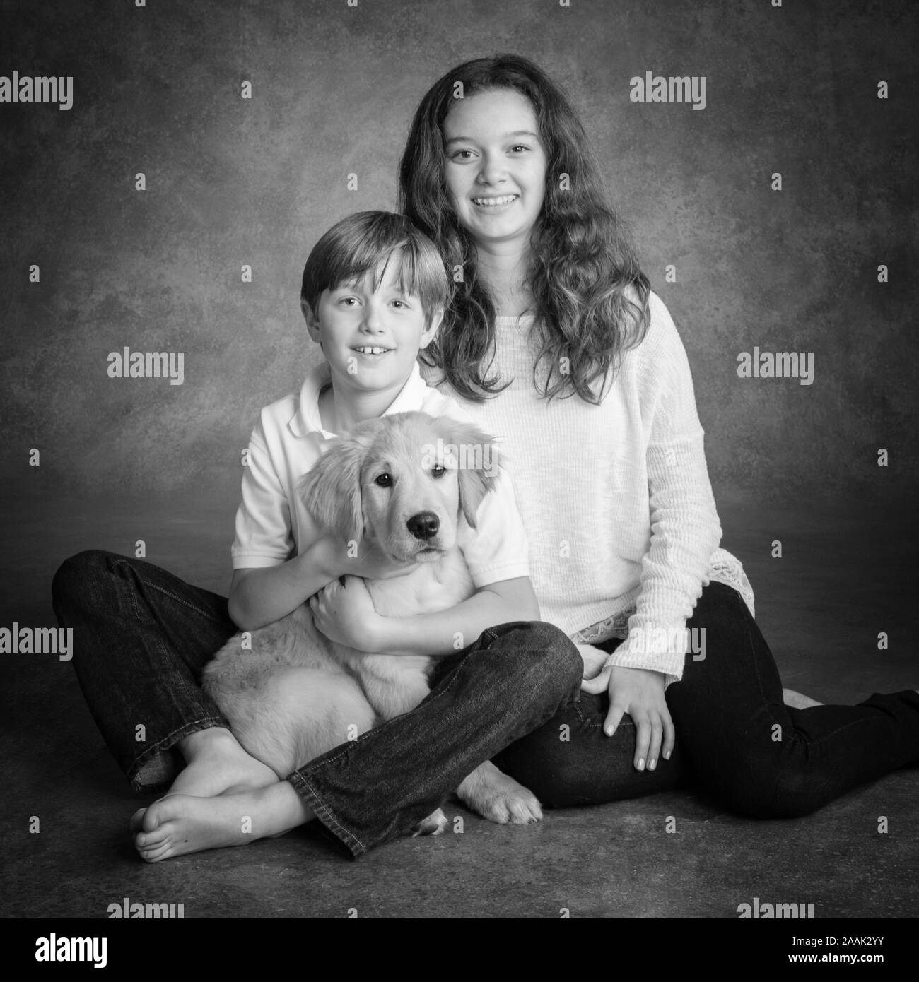 Portrait of brother and sister with Golden Retriever puppy Stock Photo