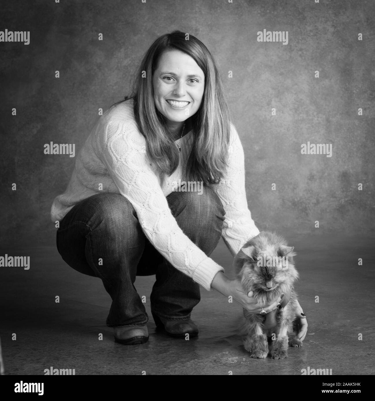 Studio portrait of smiling woman with long-haired cat Stock Photo