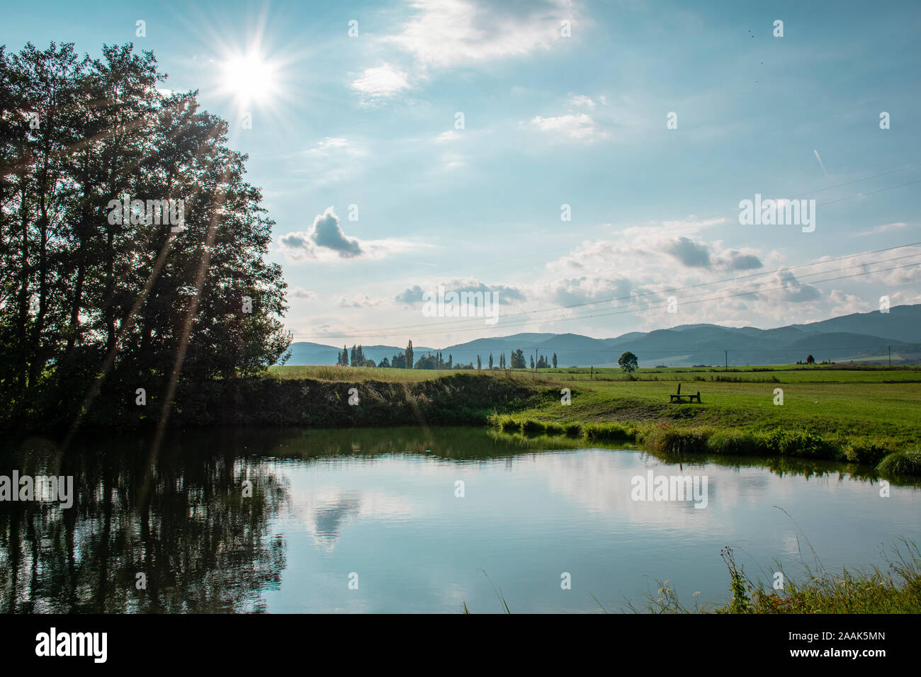Shining sun over the fish pond in Diviaky, Slovakia in beautiful summer day. Reflection in the water. Stock Photo