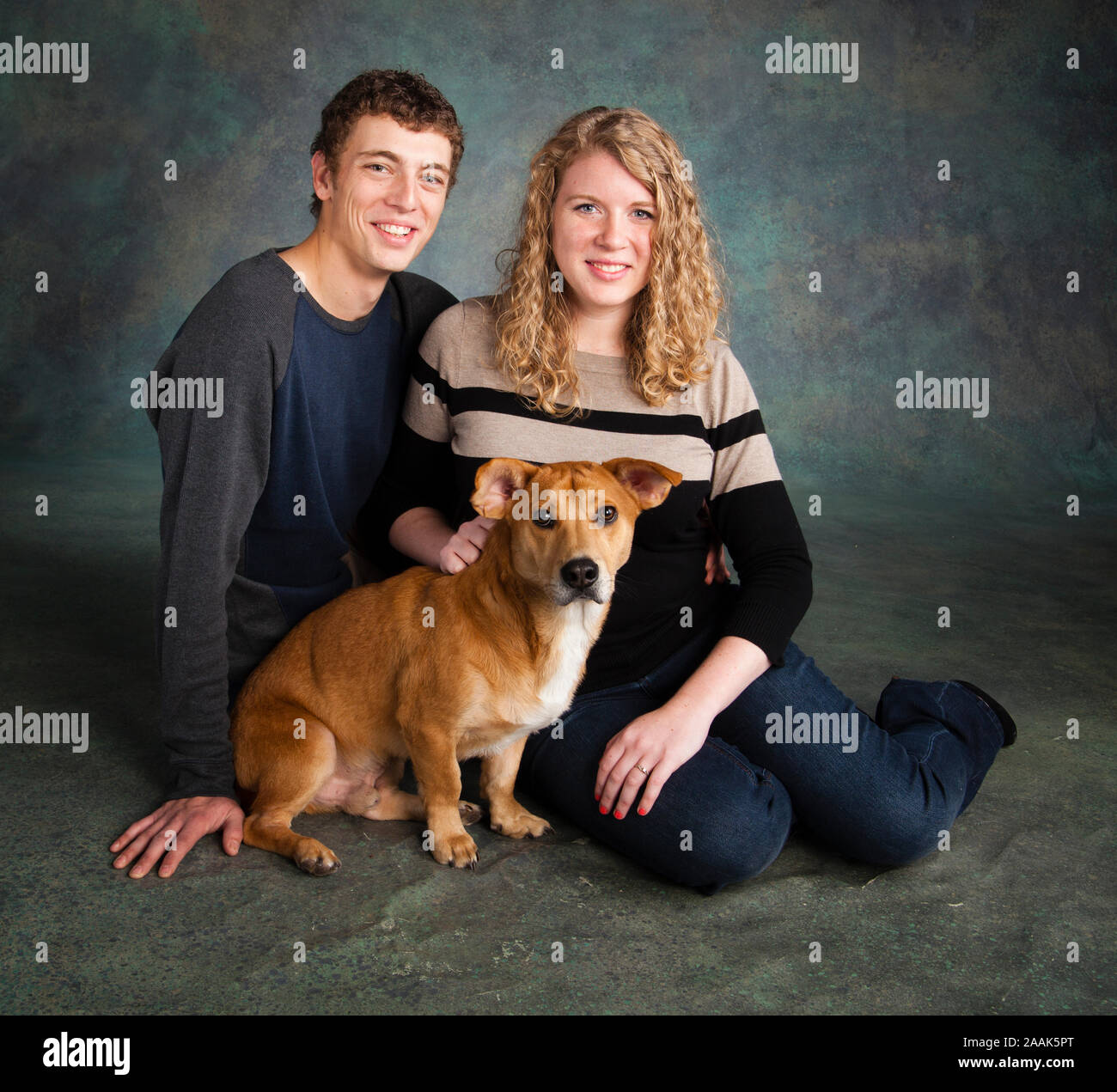 Studio portrait of smiling couple with Westie Labrador mixed dog Stock Photo