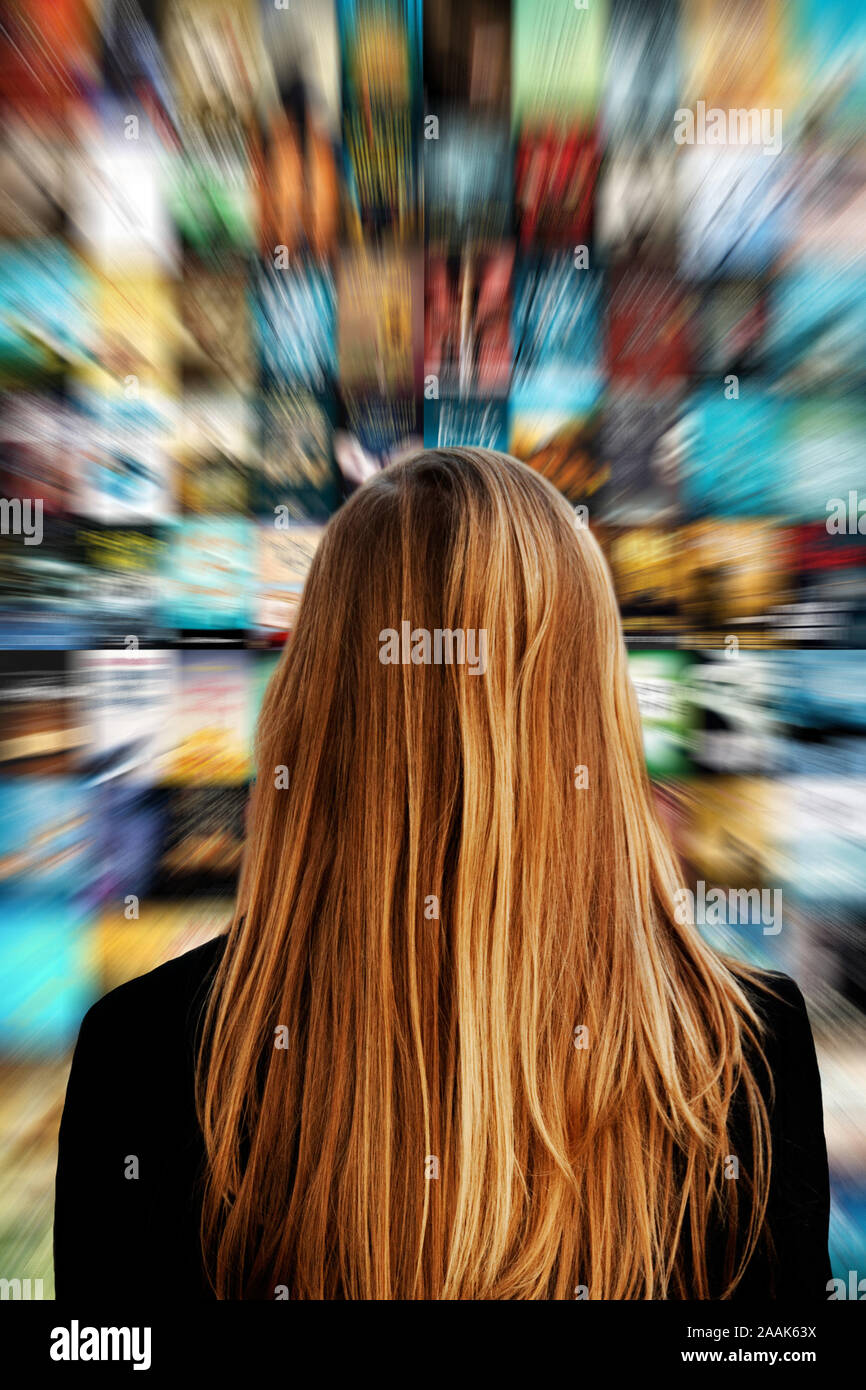 young blond woman looking at a screen with images, concept for streaming media  and social media Stock Photo