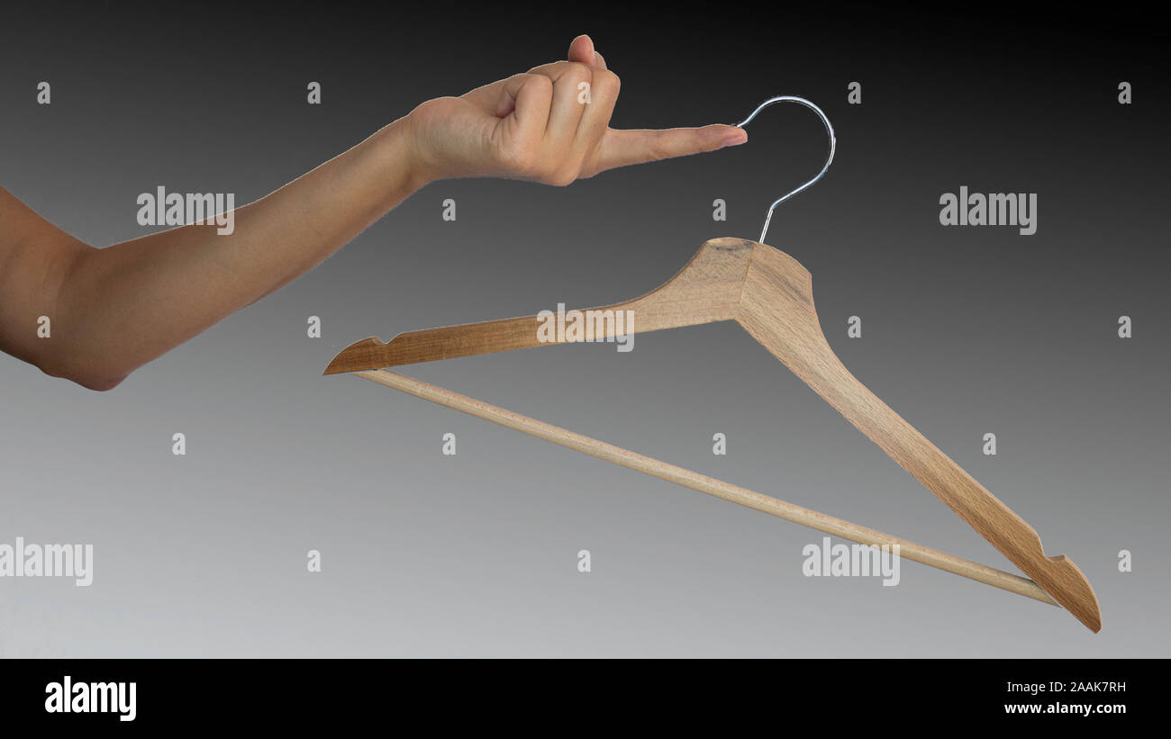 Wooden clothes hanger hanging from a female finger on a black background. Advertising of Black Friday sales. Stock Photo