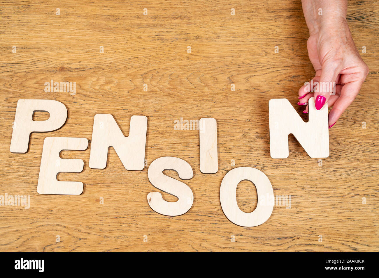 old woman hands laid out the word pension on a wooden board Stock Photo