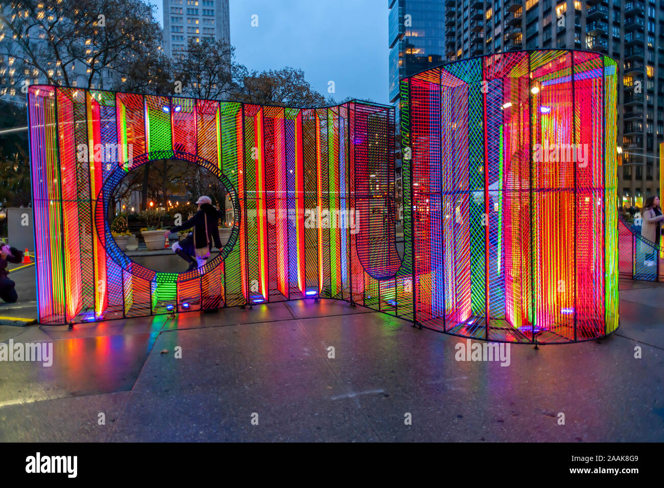 Visitors to Flatiron Plaza in New York on Monday, November 18, 2019 interact with “Ziggy” created by Hou de Sousa. The Christmas installation is the centerpiece of the Flatiron/23rd Street Partnership's holiday programming, “23 Days of Flatiron Cheer”. “Ziggy” contains 27,000 feet of iridescent cord illuminated by uv lighting. (© Richard B. Levine) Stock Photo