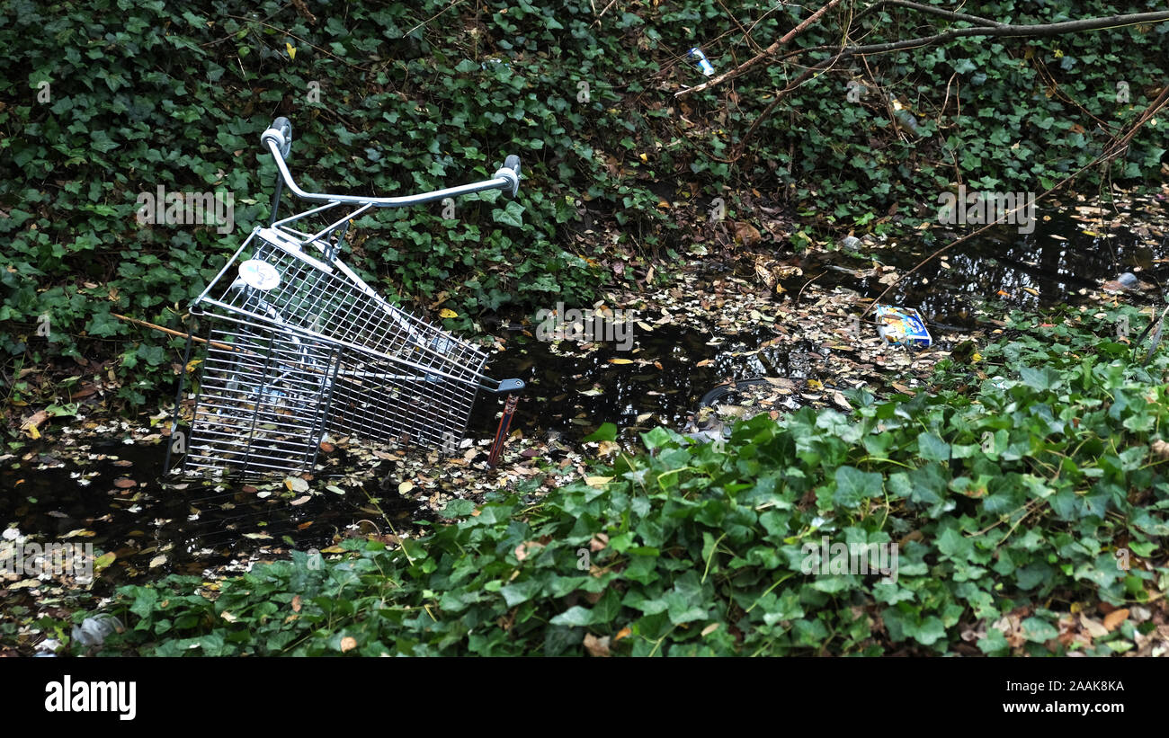 Abandoned supermarket trolly UK: a supermarket trolly dumped into a local rhyne where’s its been left to damage the local environment. Stock Photo