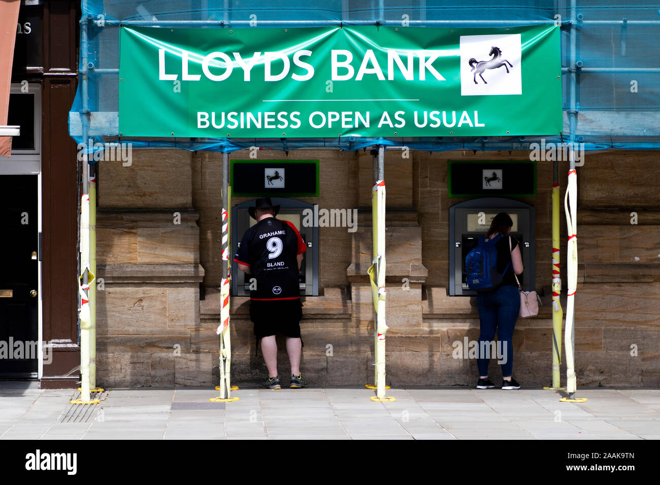 people withdrawing money from Lloyds cash point machines, British retail and commercial bank with branches across England and Wales Stock Photo