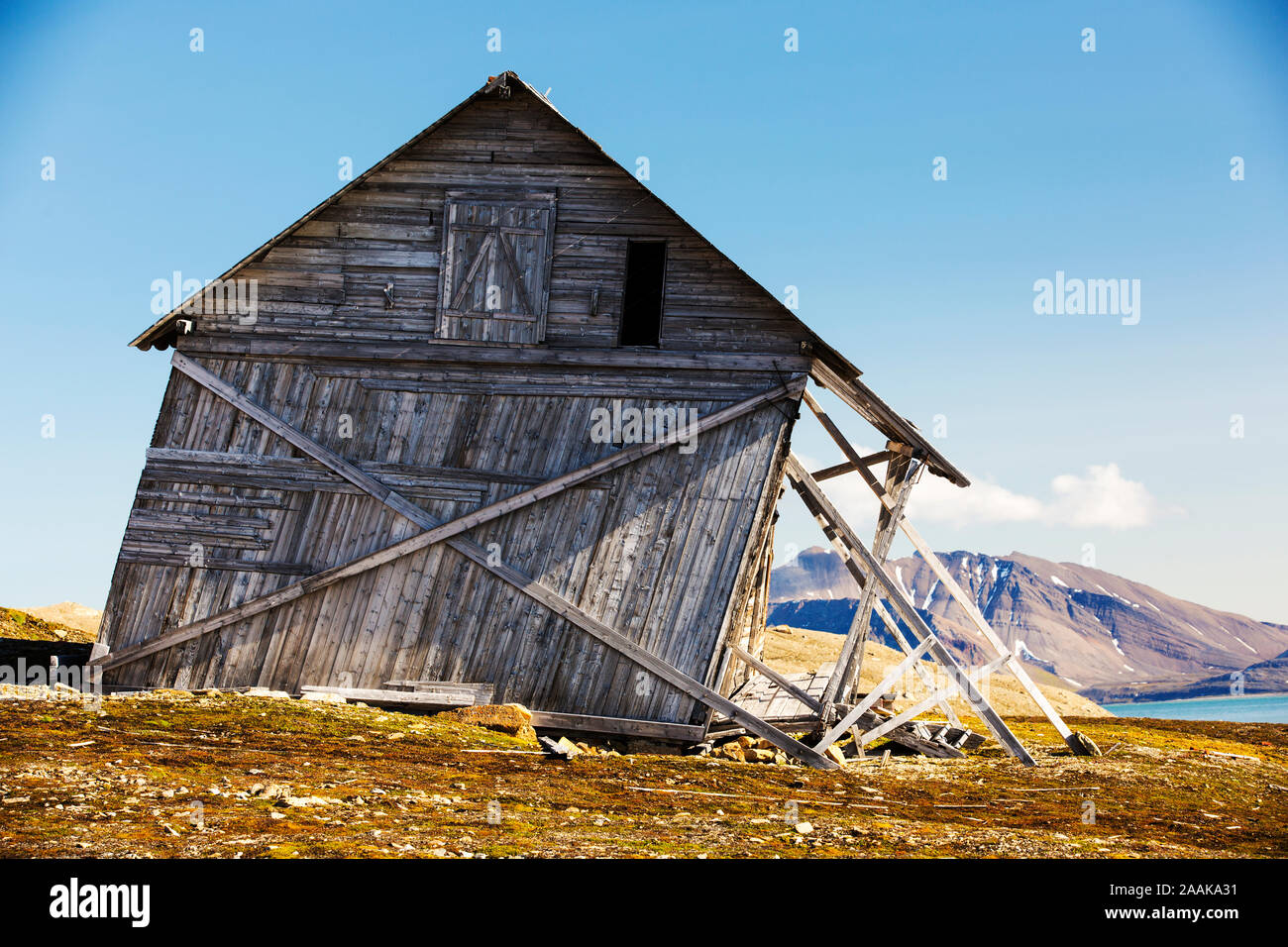 An old house at Recherchefjorden (77°31’n 14°36’e), Van Keulenfjorden, Spitsbergen, Svalbard gradually sliding down slope due to solifluction and perm Stock Photo