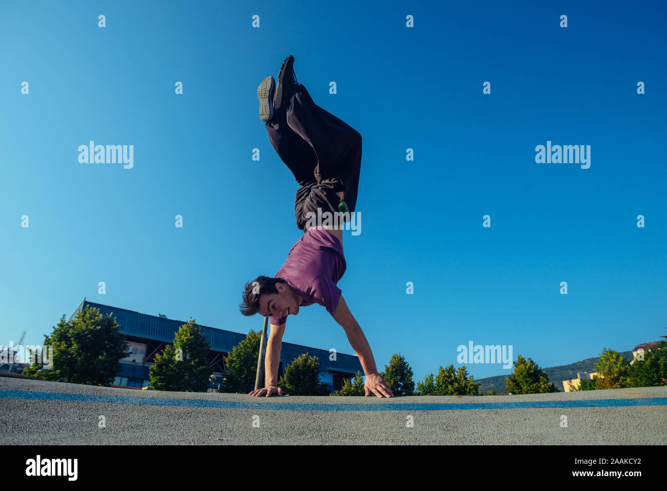 Sports man supporting his body while doing a handstand at the city