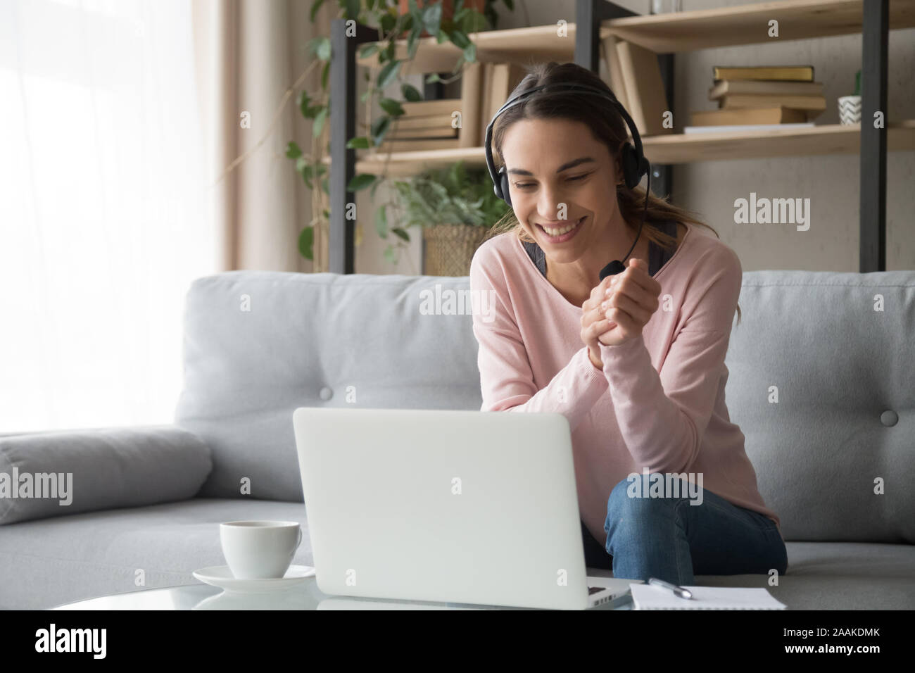 Smiling woman watching webinar sitting on couch at home Stock Photo