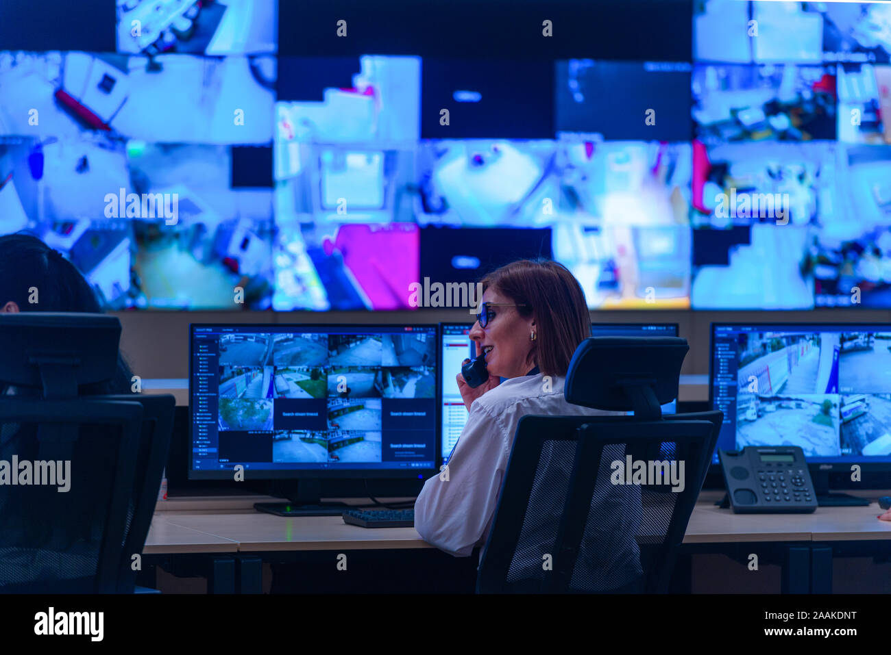 Team working on the System Control Room, Technical Operator Works at His Workstation with Multiple Displays, Security guards working on multiple monit Stock Photo