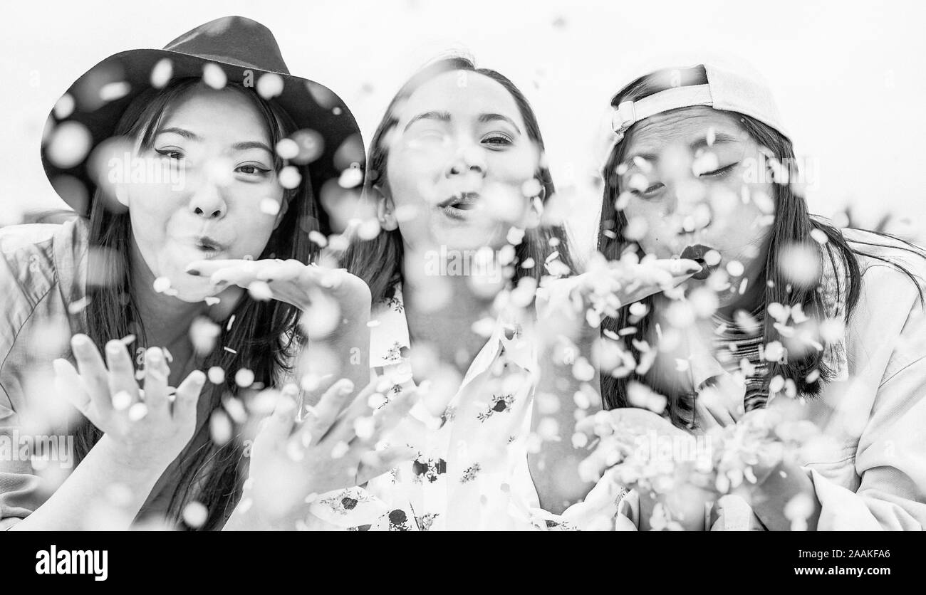 Happy Asian friends having fun throwing confetti outdoor - Young trendy people celebrating at festival event outside Stock Photo