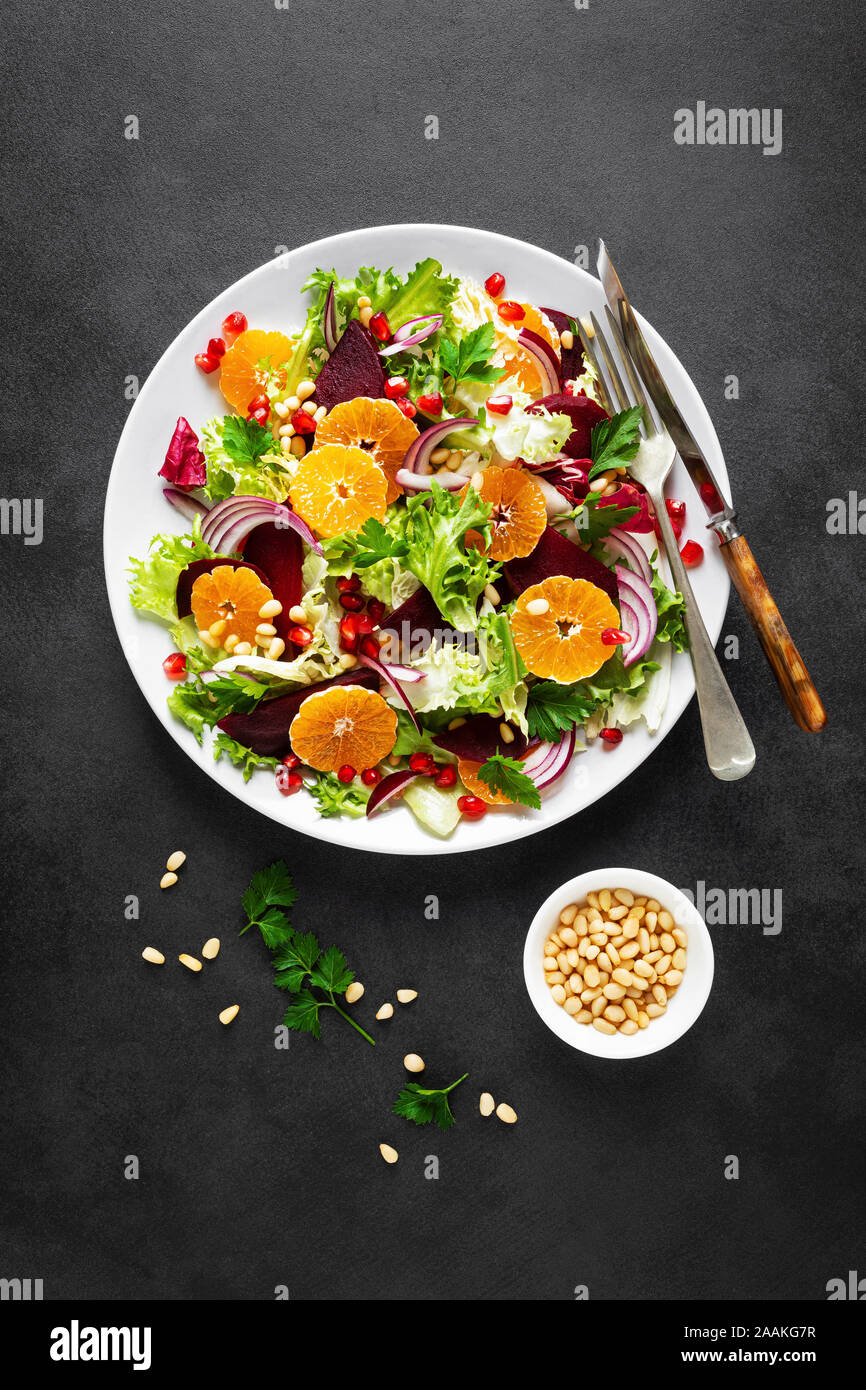 Christmas salad with boiled beet, red onion, tangerines, pomegranate, parsley, pine nuts and lettuce leaves Stock Photo