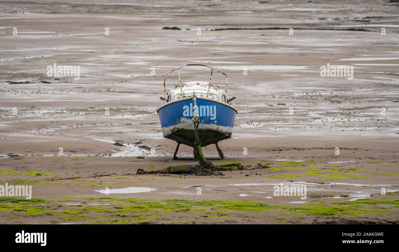 A boat in the mud of the Walney Channel, seen from the road to Roa Island, Cumbria, England, UK Stock Photo