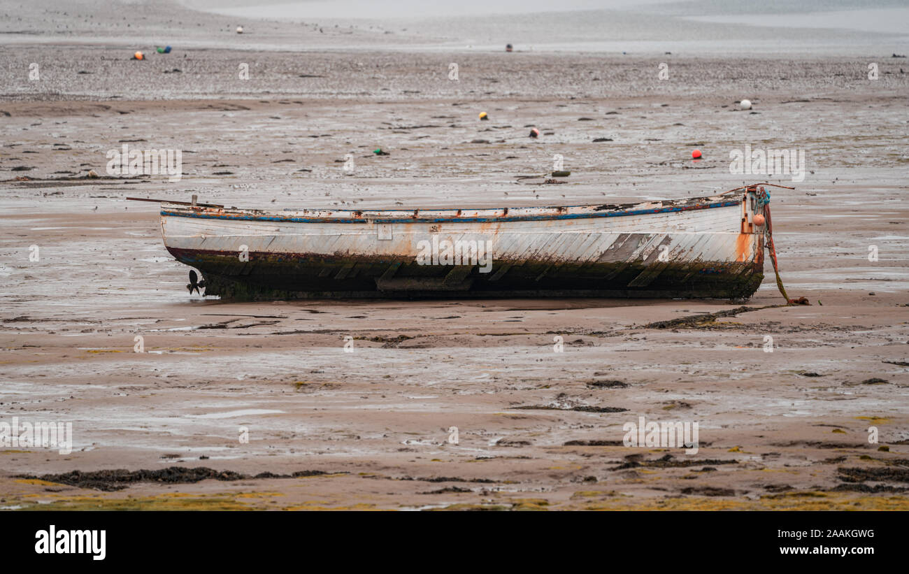 A boat in the mud of the Walney Channel, seen from the road to Roa Island, Cumbria, England, UK Stock Photo