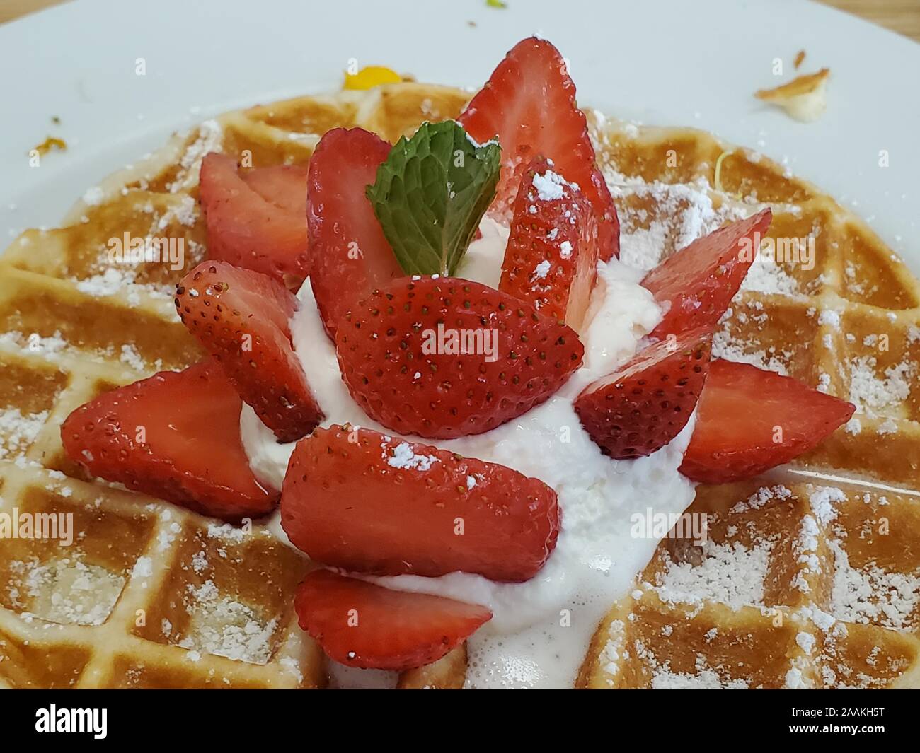 Close-up of Belgian waffle with sliced strawberries and whipped cream ...
