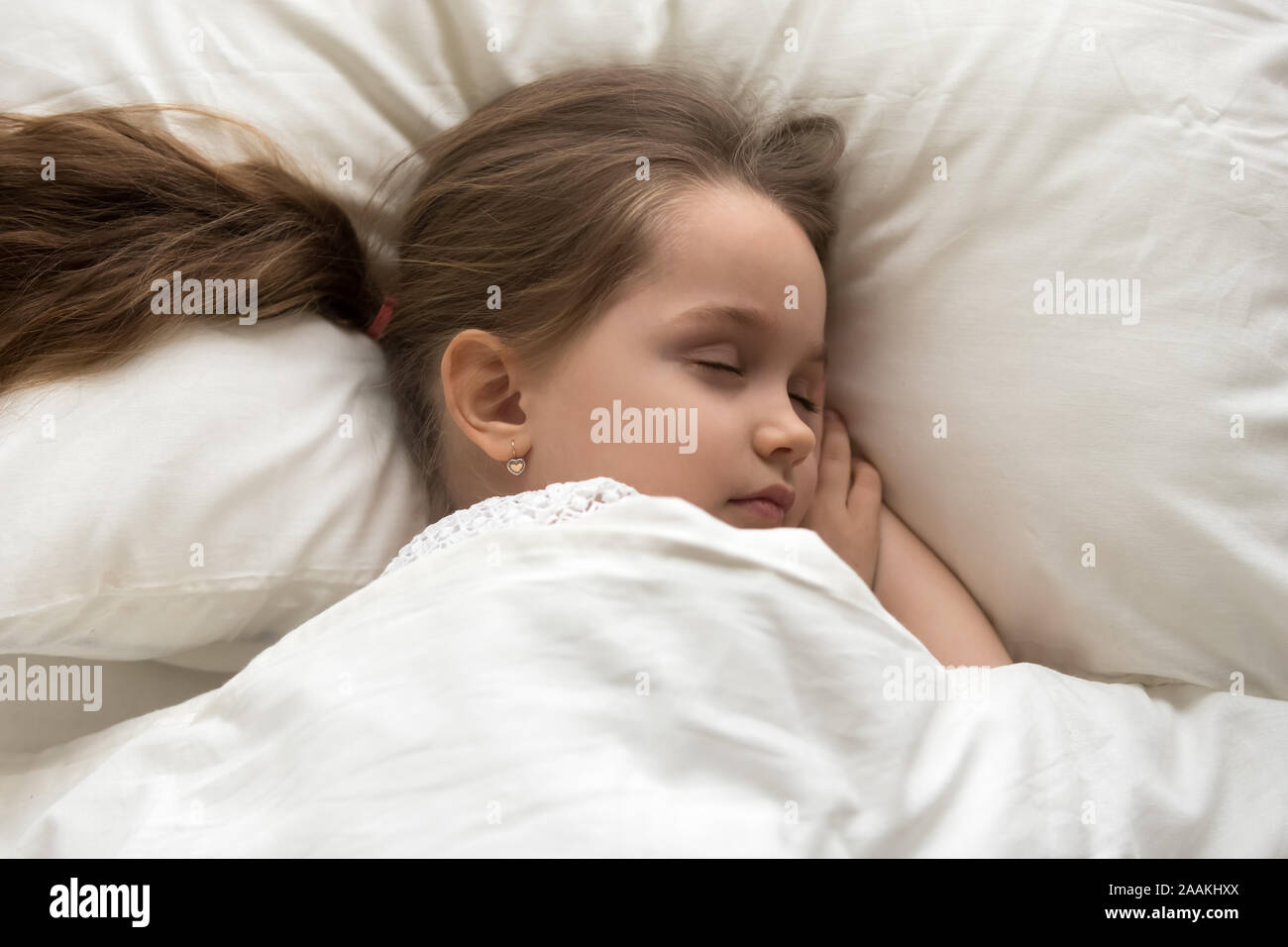 Peaceful little girl sleeping in cozy white bed Stock Photo - Alamy