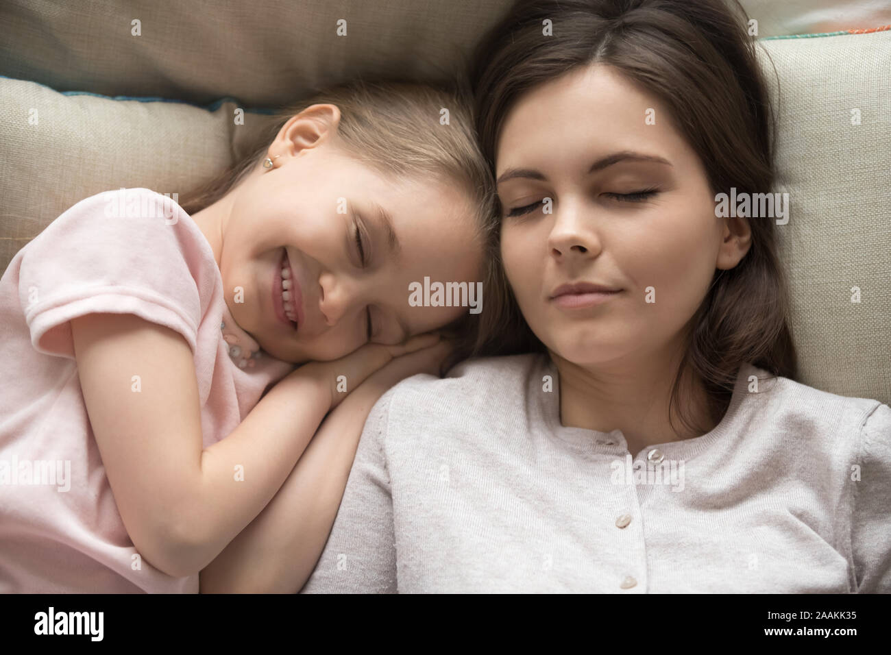 Young mom sleeping relaxing in bed with cute little daughter Stock Photo