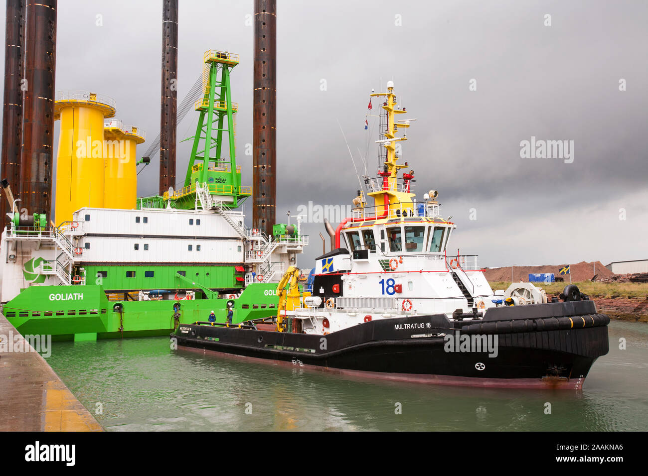 The jack up barge, Goliath, loaded with transition pieces for the Walney Offshore wind farm project, is towed out into the Walney channel by a high po Stock Photo