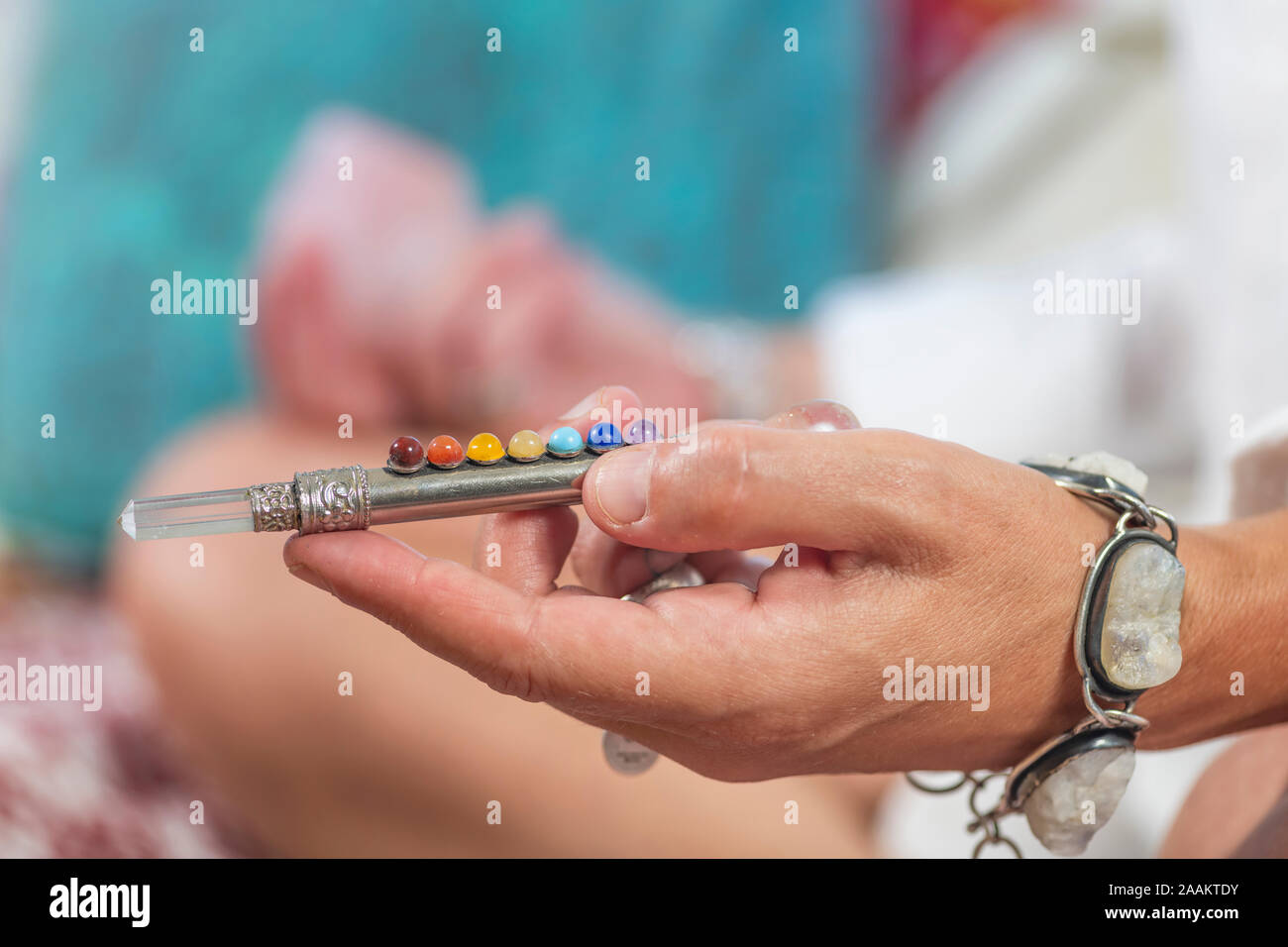Female hand holding 7 chakra healing wand for healing chakra energy points and meditation. Stock Photo