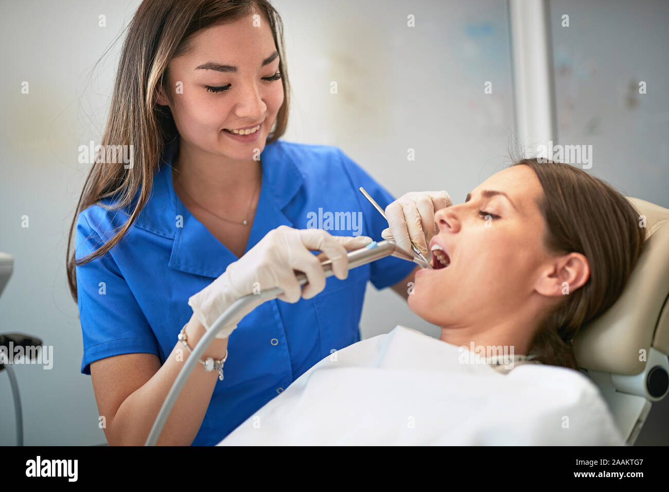 Young woman during the dental procedure with smiling dentist Stock