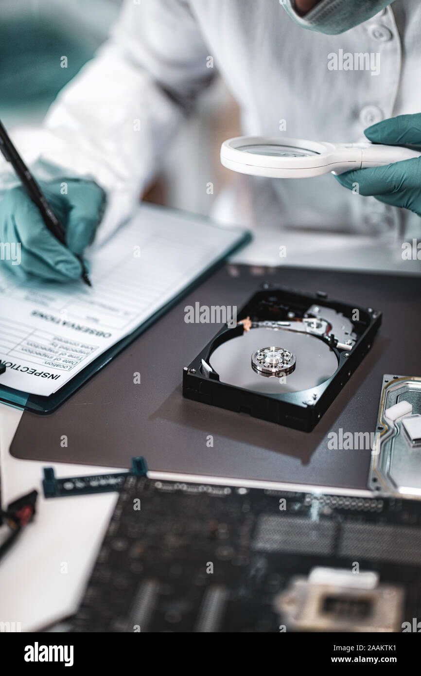 Forensic science investigator examining computer hard drive 