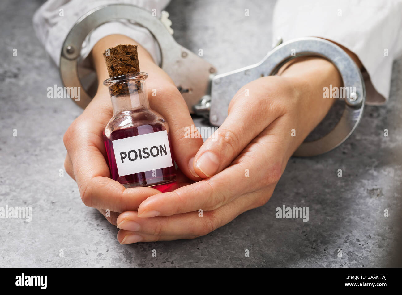 The detention of an employee of a chemical laboratory for the illegal production of toxic substances. Handcuffed hands with a bottle of poison Stock Photo