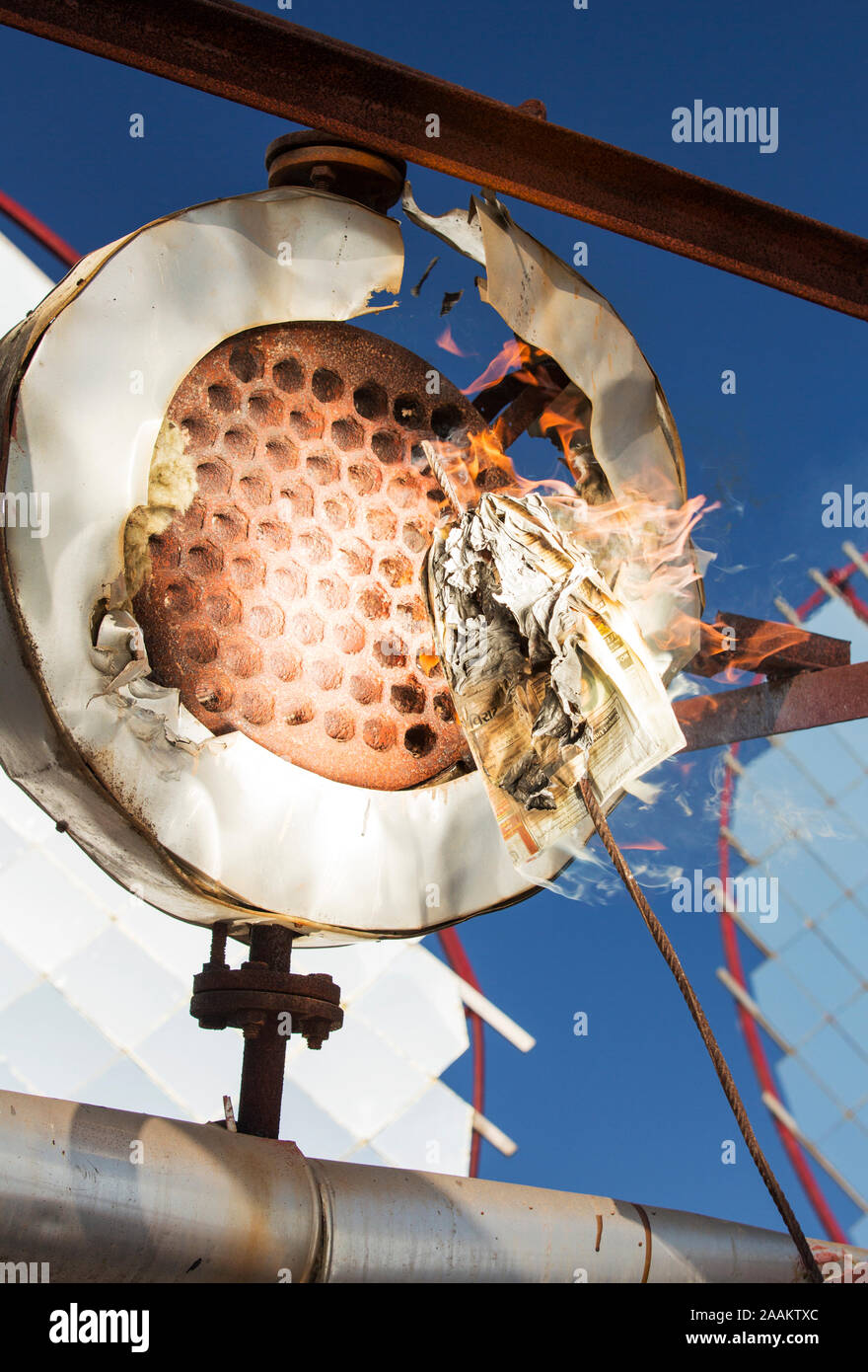 A newspaper is held in front of the rays from solar concentrating mirrors that instantly sets on fire in the 300 degrees celsius heat. Muni Seva Ashra Stock Photo