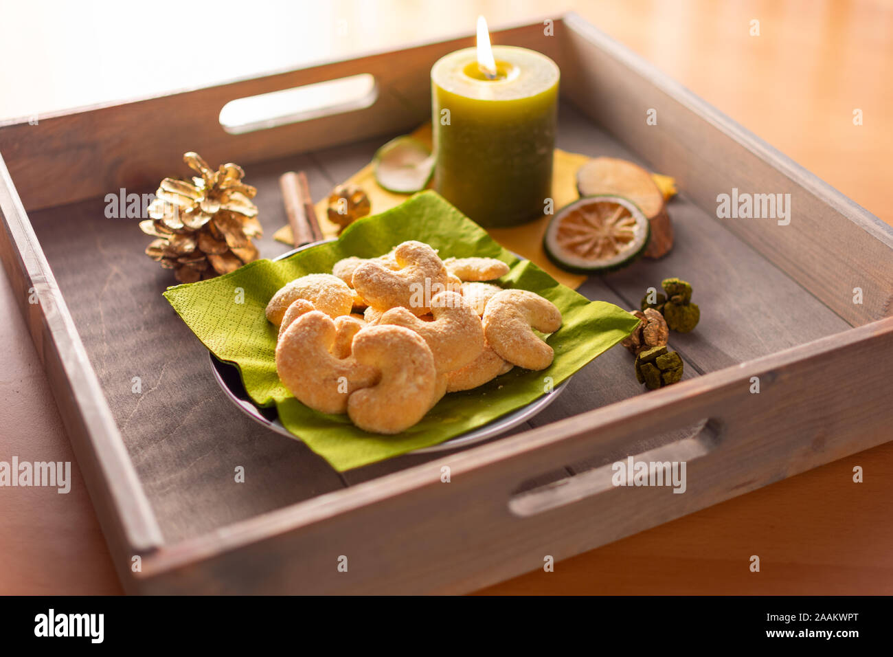 Plate of vanilla crescents on a wooden tray with candle and Christmas