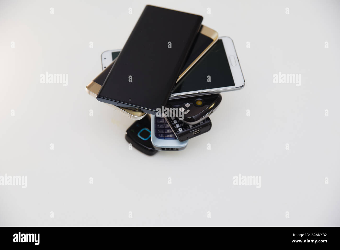 Handsets piled up in a spiral form showing the evolution back from GSM and 3G and 4G models up to 5G technology used on newer smartphones and devices Stock Photo