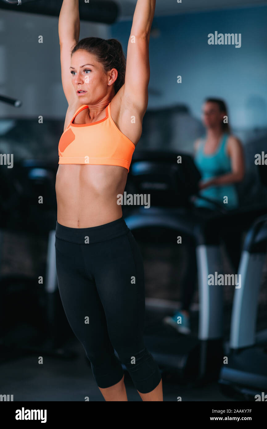 Female athlete doing pull-ups in the gym. Stock Photo