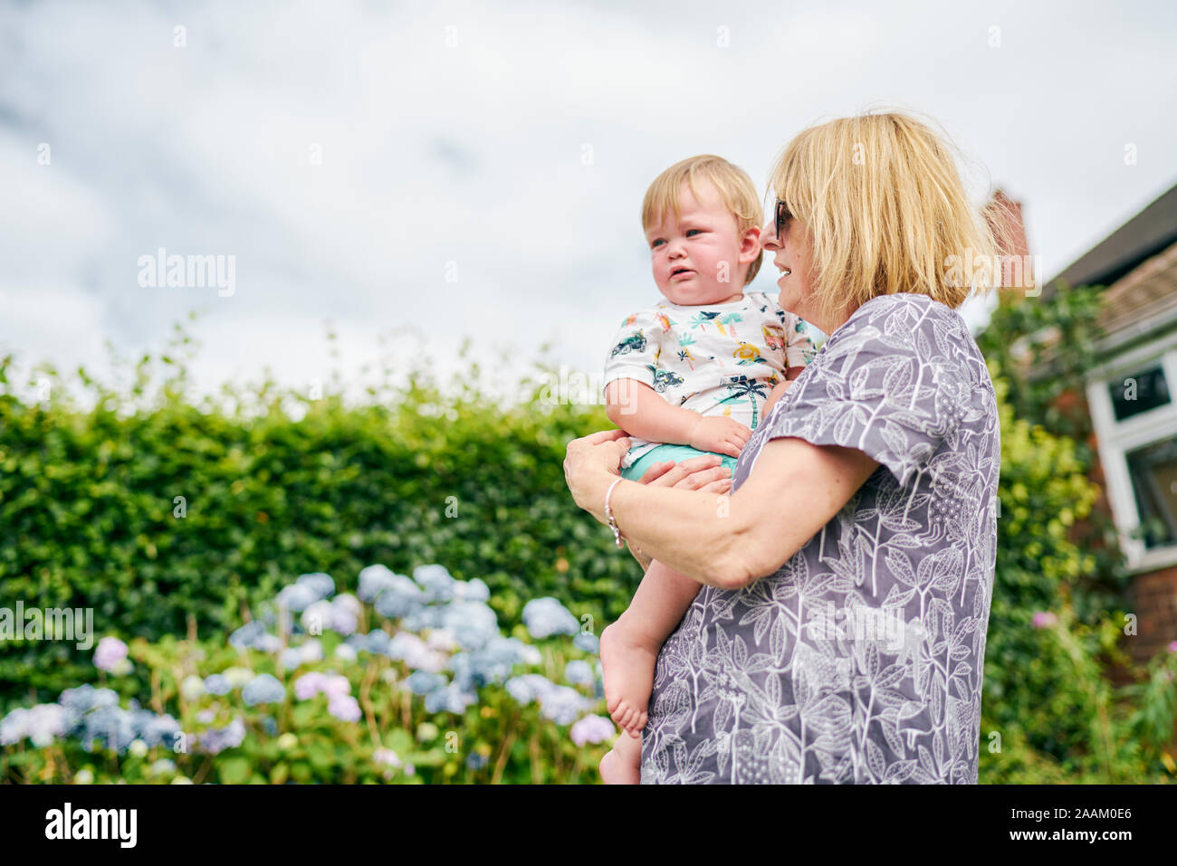 Grandmother carrying baby girl in garden Stock Photo Alamy