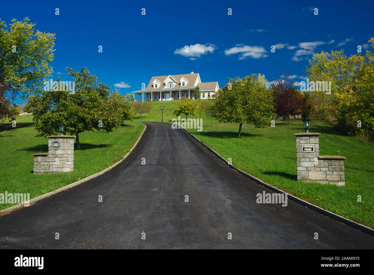 Long paved driveway leading to a house on the hill, Terrebonne, province of Quebec, Canada. Stock Photo