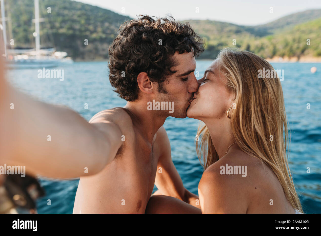 Couple taking selfie and kissing by seaside, Italy Stock Photo