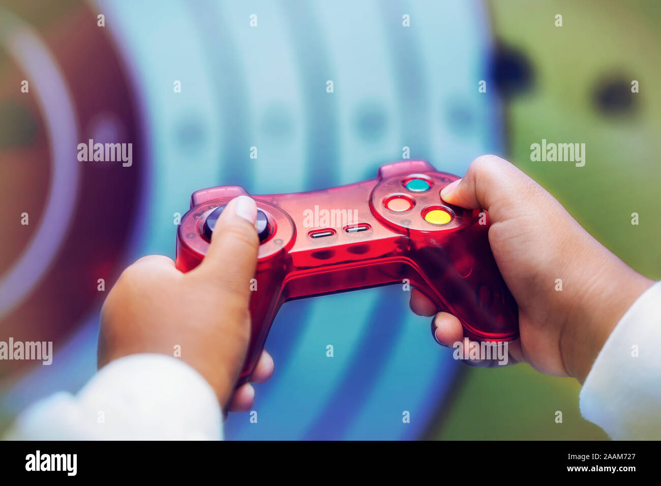 A child playing a shooting genre video game, close-up of the hands holding the controller and pushing buttons. Stock Photo