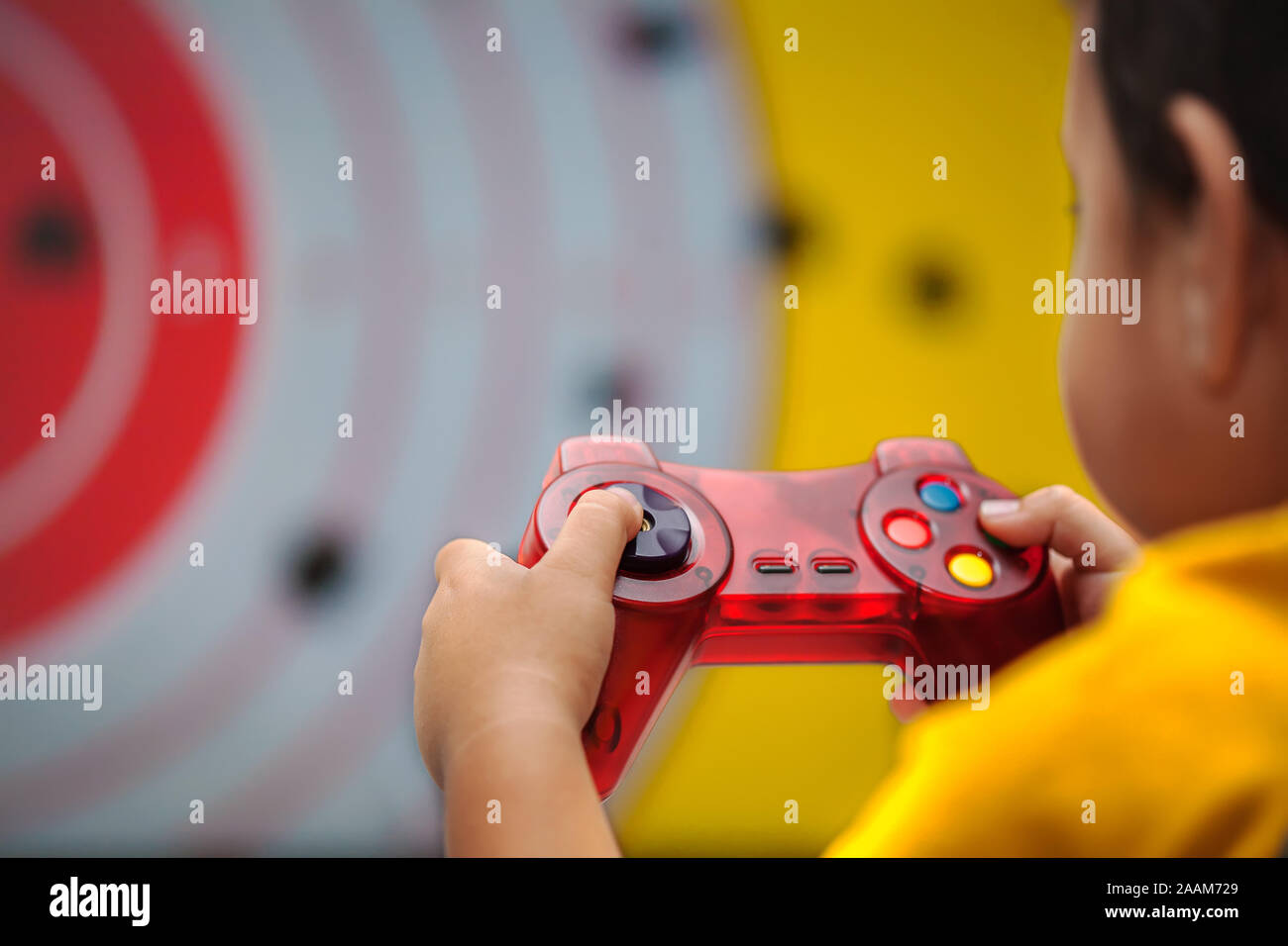 Young boy holding a generic gamepad while playing a violent genre video game. Stock Photo