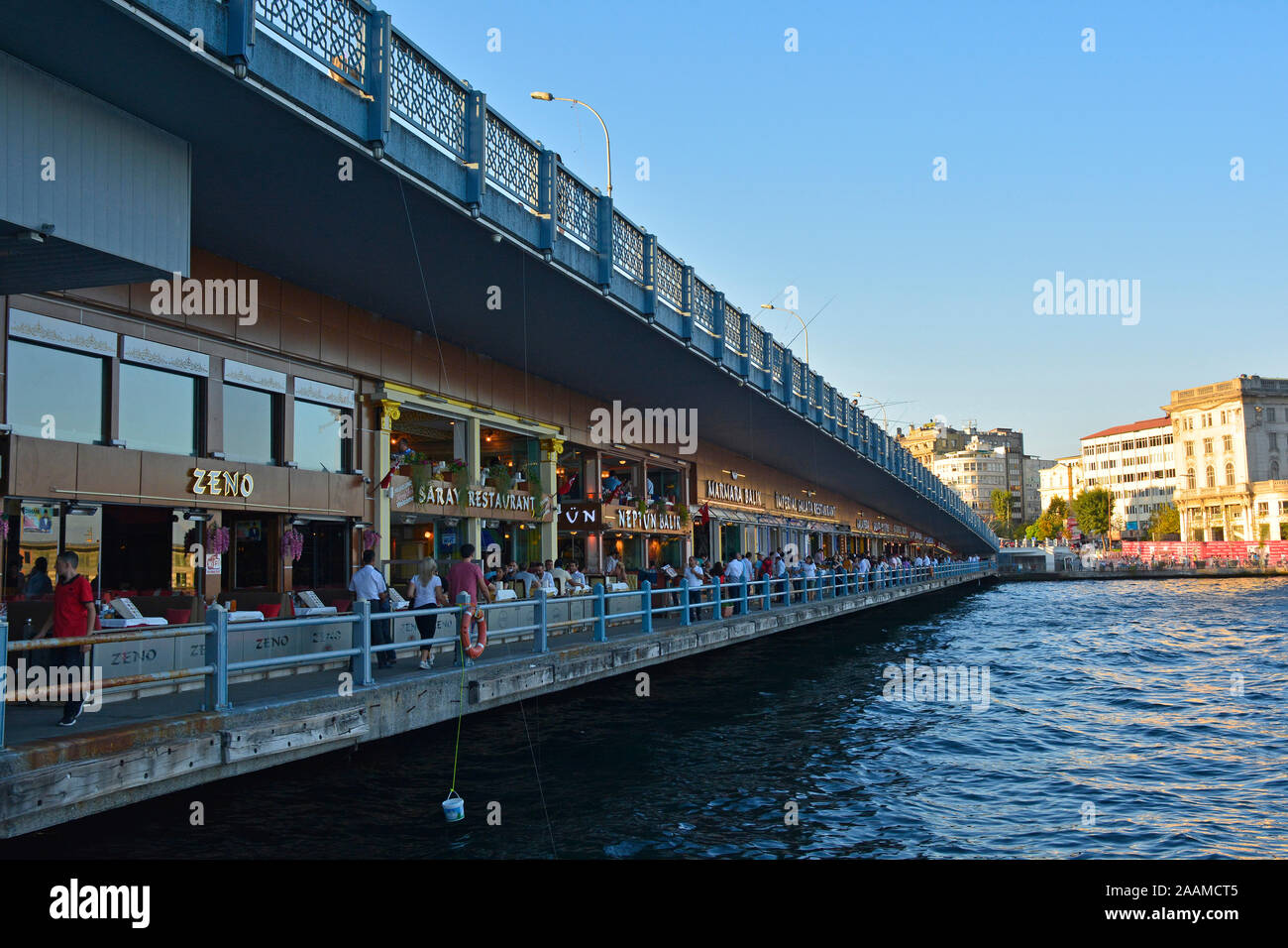 Istanbul, Turkey - September 6th 2019. Locals and tourists walk past resturants on the lower walkway of the Galata Bridge spanning the Golden Horn Stock Photo
