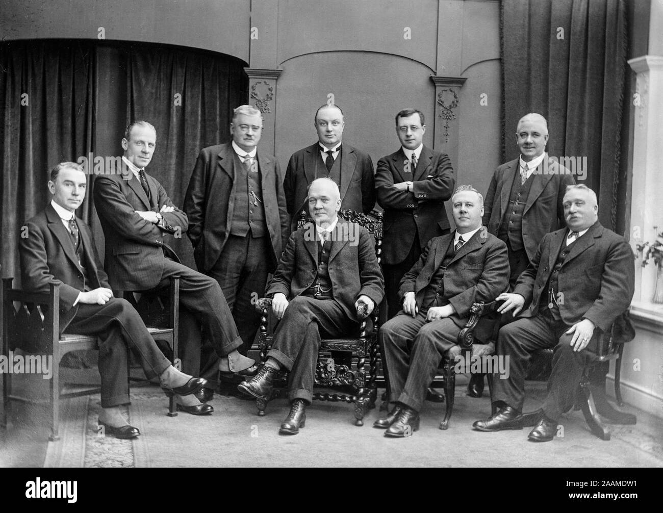 An early Edwardian English vintage black and white photograph showing a group of men, some seated, some standing, indoors. Shows the fashion of the period. Stock Photo