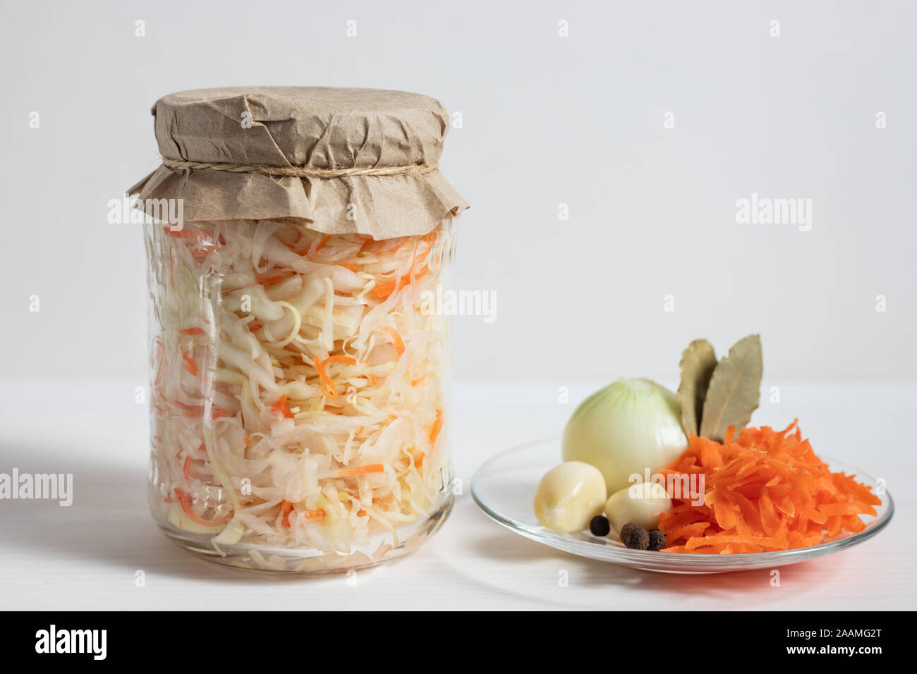 Homemade sauerkraut. Fermented food. Sauerkraut with carrots in a glass jar on a white wooden background. Stock Photo