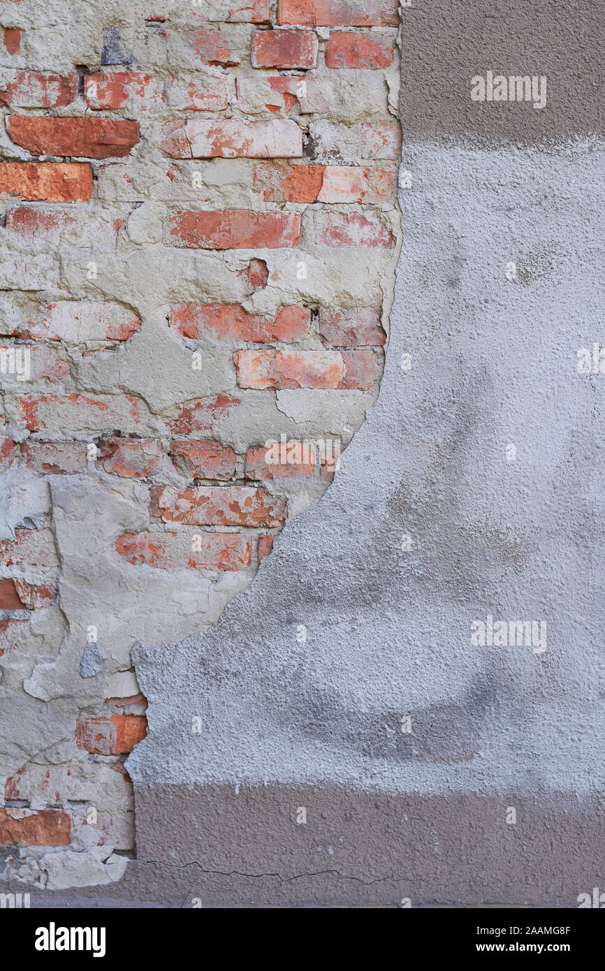 Old weathered red brick wall fragment, crumbling plaster Stock Photo