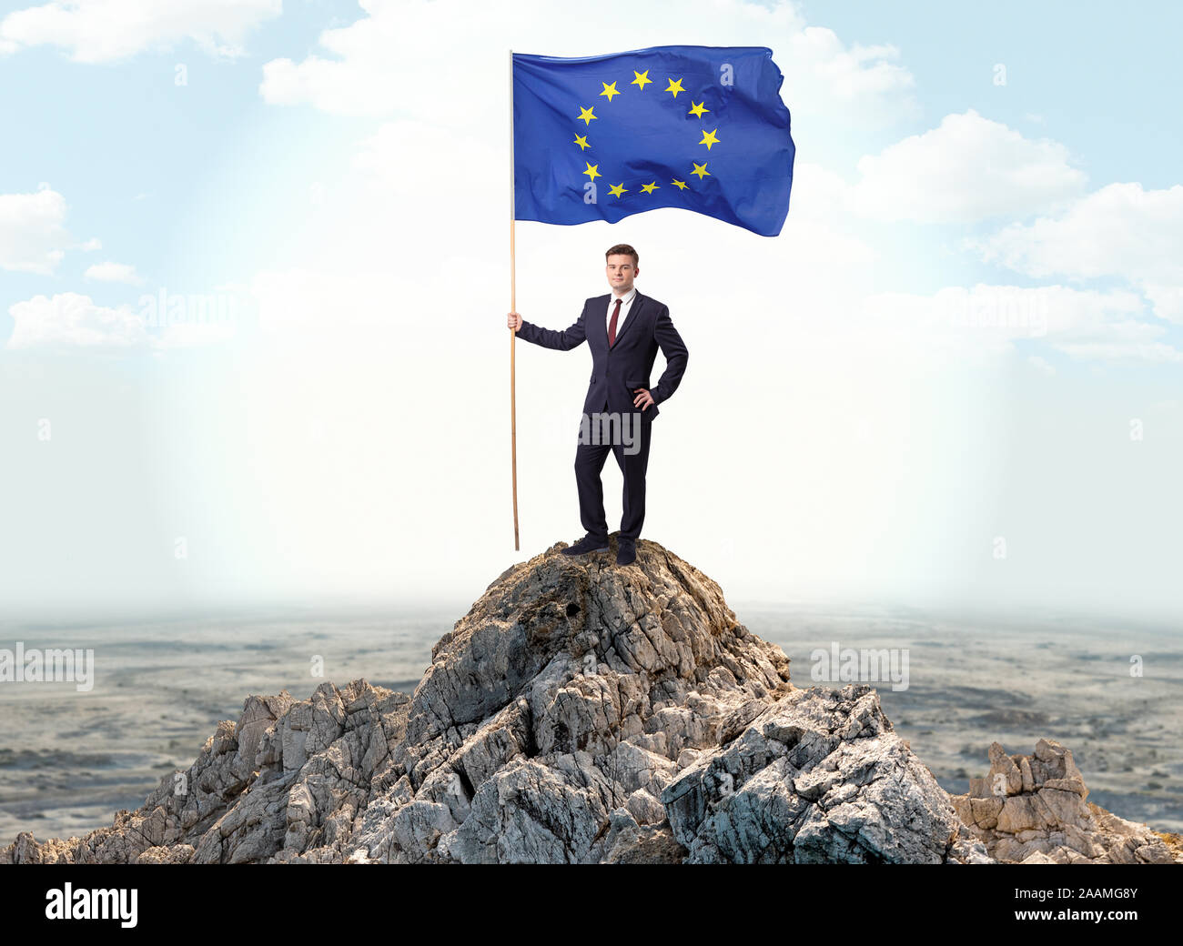 Successful businessman on the top of a mountain holding victory flag ...