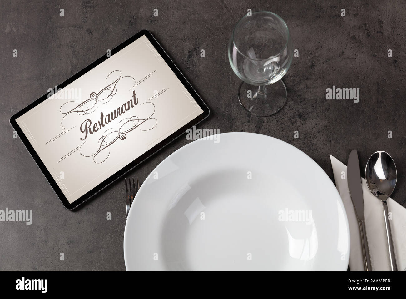 Tablet with stylish restaurant logo and laid table Stock Photo