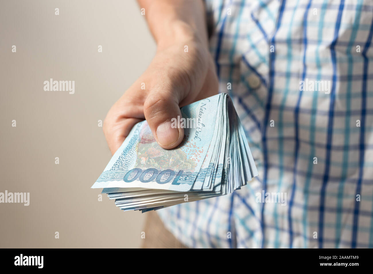 Hand holding giving cash banknote of one thousand Philippines peso paying bills, payment procedure or bribe, salary Stock Photo